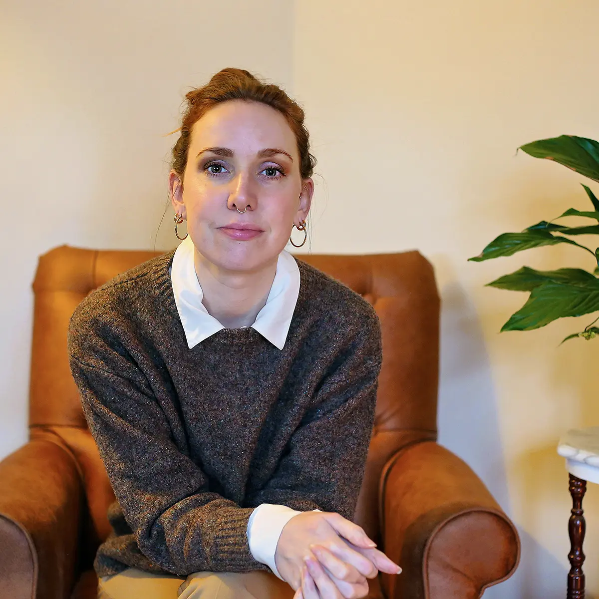Woman sitting in brown armchair indoors