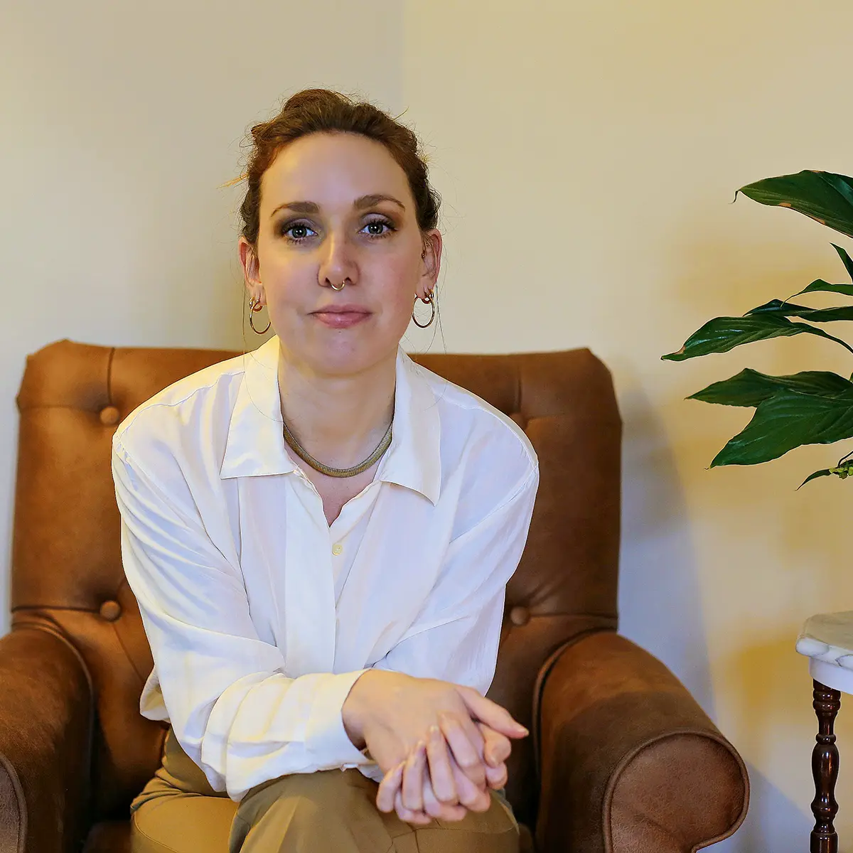 Woman sitting in brown leather armchair indoors
